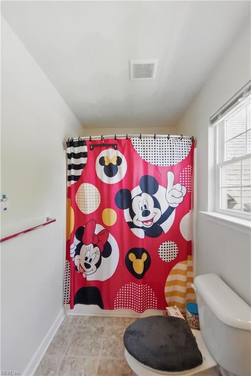full bathroom with toilet, a shower with shower curtain, baseboards, and visible vents