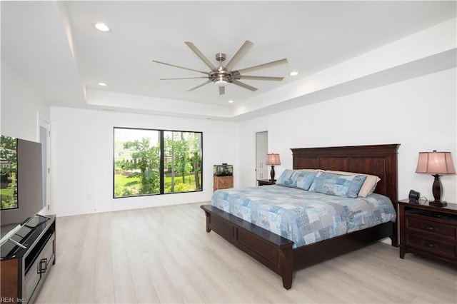 bedroom featuring ceiling fan, light wood-style floors, a tray ceiling, and recessed lighting