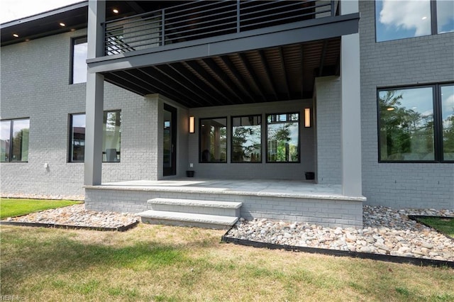 property entrance featuring brick siding and a balcony