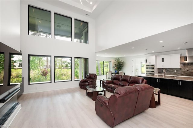 living area featuring light wood finished floors, a high ceiling, and recessed lighting