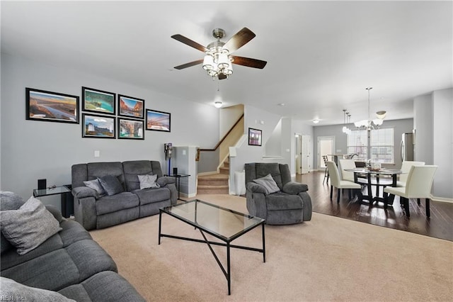 carpeted living room featuring stairway, a ceiling fan, wood finished floors, and baseboards