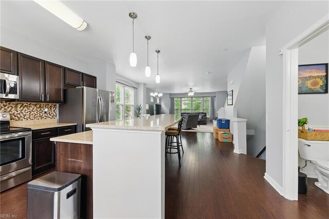 kitchen with stainless steel appliances, open floor plan, a center island, dark brown cabinetry, and a kitchen bar