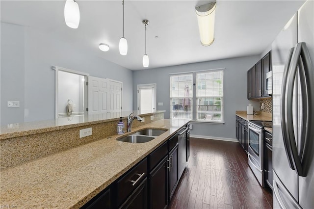 kitchen with stainless steel appliances, a sink, dark wood-style flooring, pendant lighting, and light stone countertops