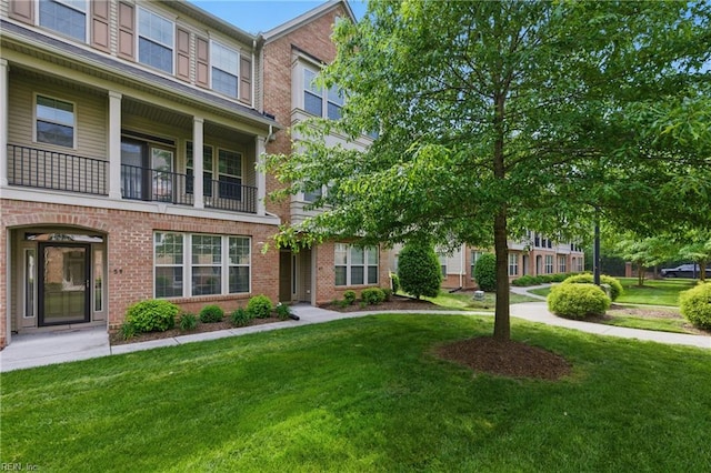 townhome / multi-family property with a front yard and brick siding