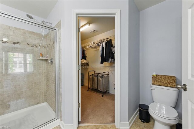 bathroom featuring a shower stall, a spacious closet, toilet, and baseboards