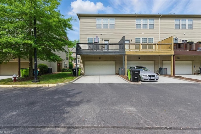 back of house with an attached garage, driveway, and central AC unit