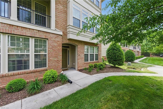 view of exterior entry with a yard and brick siding
