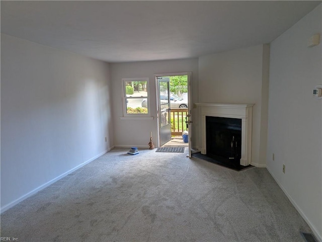 unfurnished living room with carpet, baseboards, a fireplace with flush hearth, and visible vents