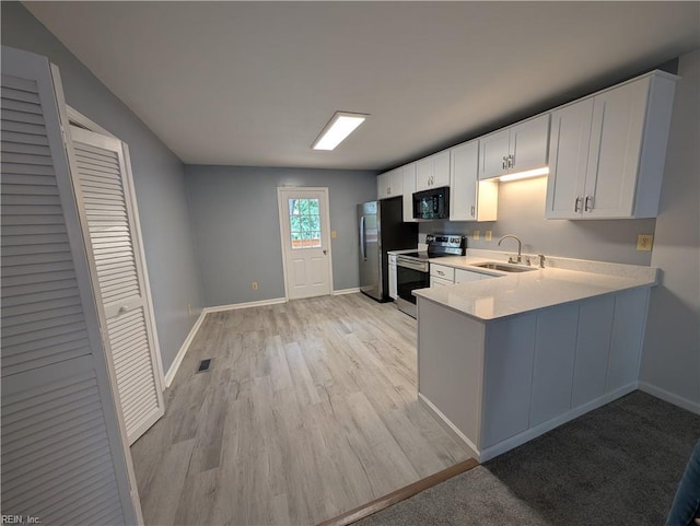 kitchen with a sink, light wood finished floors, light countertops, baseboards, and appliances with stainless steel finishes