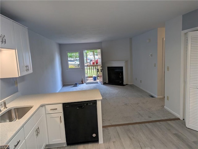 kitchen with a sink, a peninsula, dishwasher, open floor plan, and a fireplace with flush hearth
