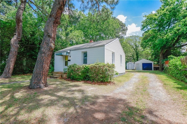 48 Pollux Cir W, Portsmouth, VA 23701 - view of front facade with a chimney, driveway, an outdoor structure, a detached garage, and a storage unit