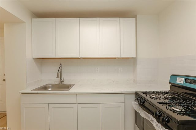 48 Pollux Cir W, Portsmouth, VA 23701 - kitchen featuring a sink, white cabinetry, light stone countertops, decorative backsplash, and gas stove