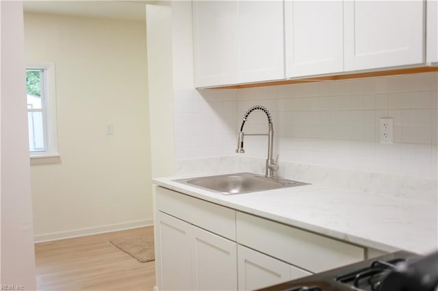 48 Pollux Cir W, Portsmouth, VA 23701 - kitchen with a sink, light wood-type flooring, white cabinetry, decorative backsplash, and baseboards