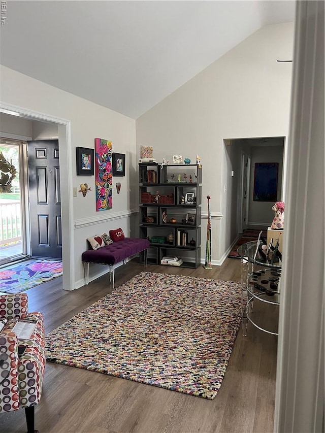 living area with vaulted ceiling, wood finished floors, and baseboards
