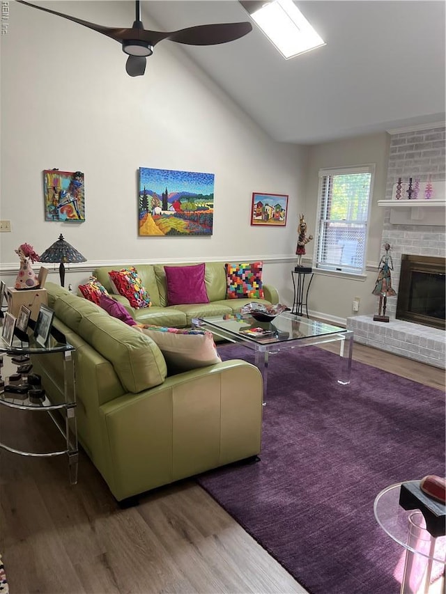 living area with a brick fireplace, wood finished floors, ceiling fan, and vaulted ceiling