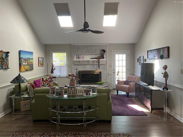 living area with ceiling fan, a brick fireplace, baseboards, and wood finished floors