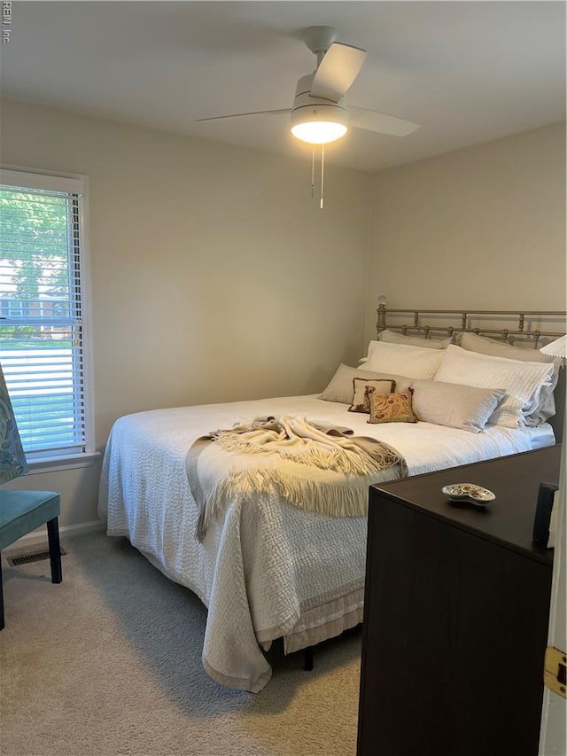 carpeted bedroom featuring multiple windows, baseboards, and ceiling fan