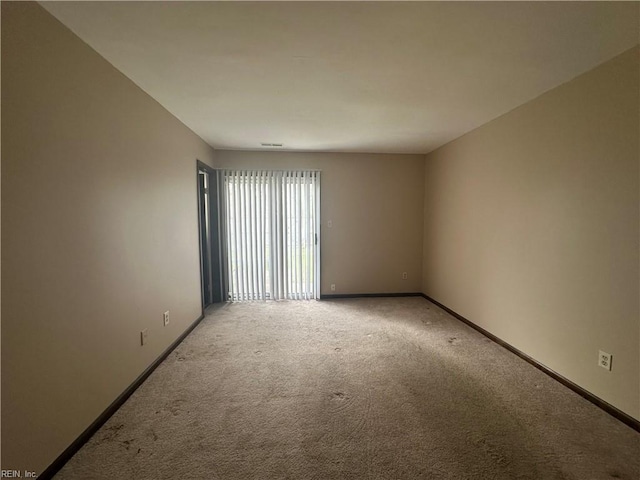 empty room featuring light carpet and baseboards