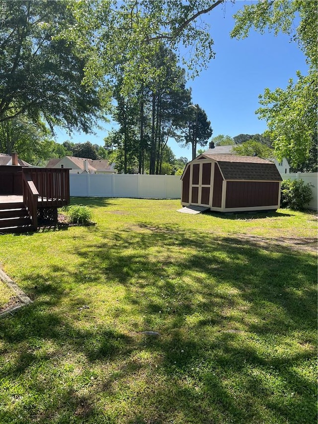 view of yard with an outdoor structure, a deck, a fenced backyard, and a storage unit