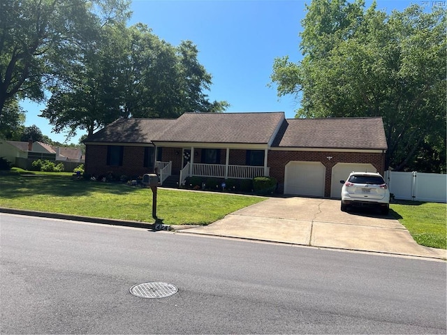 ranch-style home featuring fence, an attached garage, concrete driveway, a front yard, and a porch