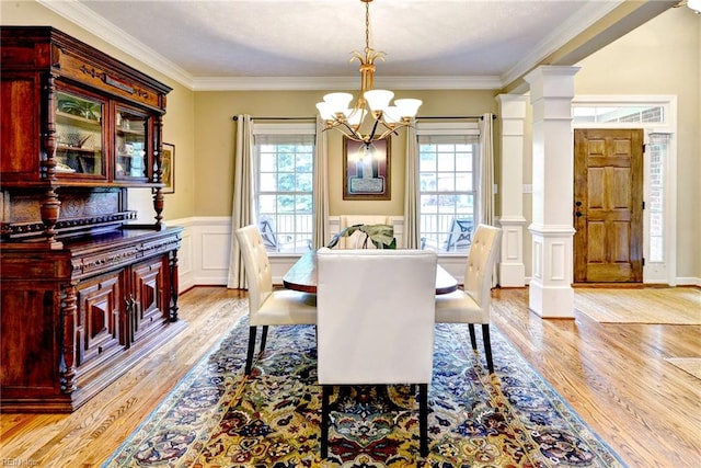 dining space with a chandelier, plenty of natural light, light wood-style flooring, crown molding, and wainscoting