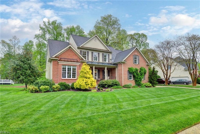 view of front of property featuring brick siding, a standing seam roof, a front lawn, metal roof, and covered porch