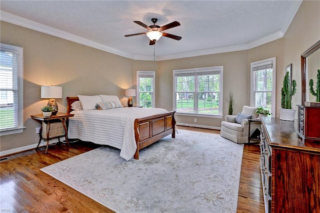 bedroom featuring wood finished floors, baseboards, ornamental molding, and a ceiling fan