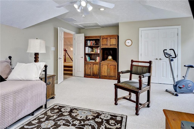 living room featuring carpet, ceiling fan, a textured ceiling, and attic access