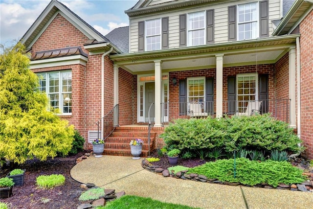 entrance to property with brick siding and a porch