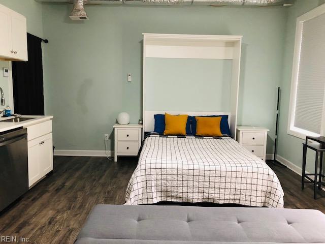 bedroom with dark wood-type flooring, baseboards, and a sink