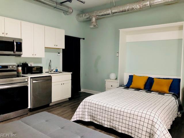 bedroom featuring baseboards, dark wood finished floors, and a sink
