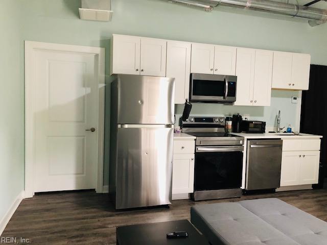 kitchen with white cabinets, appliances with stainless steel finishes, dark wood-style flooring, and a sink