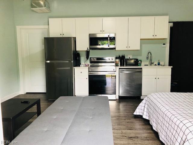 kitchen with white cabinetry, light countertops, dark wood-type flooring, and appliances with stainless steel finishes