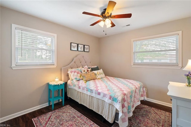 bedroom with a ceiling fan, visible vents, wood finished floors, and baseboards