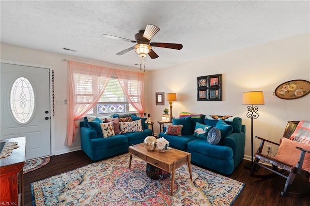 living area featuring wood finished floors, a textured ceiling, visible vents, a ceiling fan, and baseboards