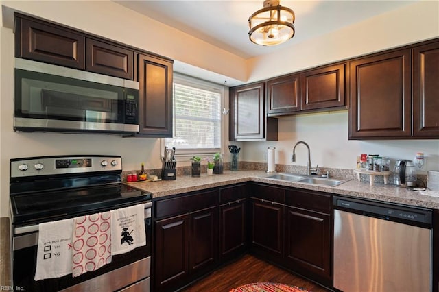 kitchen featuring dark brown cabinets, dark wood finished floors, a sink, light countertops, and appliances with stainless steel finishes