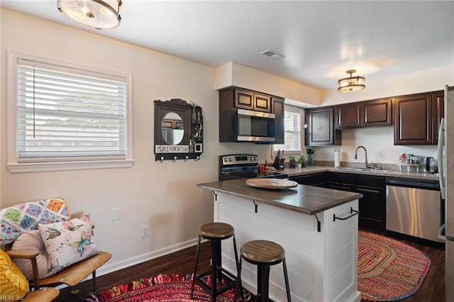 kitchen with dark wood-style flooring, visible vents, a sink, dark countertops, and stainless steel appliances