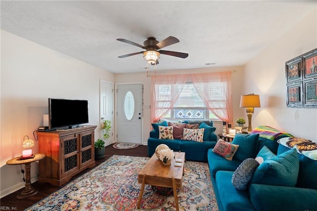 living room featuring wood finished floors, a textured ceiling, visible vents, a ceiling fan, and baseboards