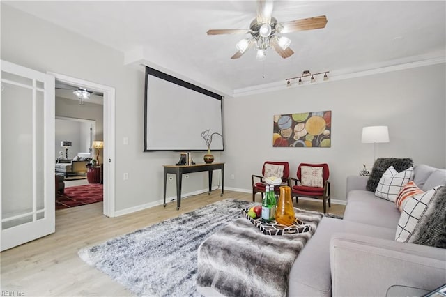 living area featuring a ceiling fan, wood finished floors, baseboards, and ornamental molding