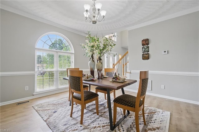 dining space with a chandelier, plenty of natural light, light wood finished floors, ornamental molding, and baseboards