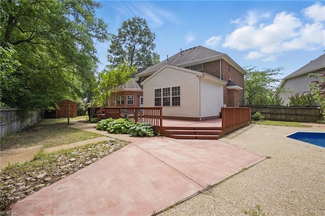 rear view of property featuring a patio area, a fenced backyard, a deck, and brick siding