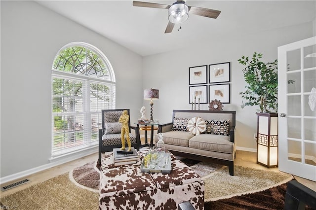 living area with ceiling fan and baseboards