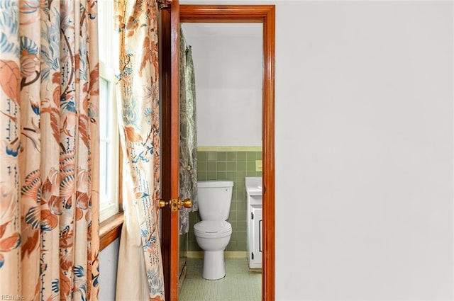 bathroom featuring tile walls, toilet, a wainscoted wall, and tile patterned floors