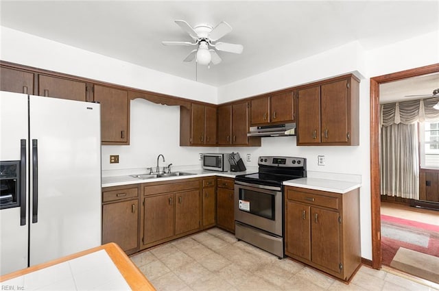 kitchen featuring appliances with stainless steel finishes, under cabinet range hood, a sink, and light countertops