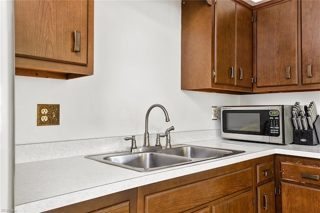 kitchen with stainless steel microwave, a sink, and light countertops