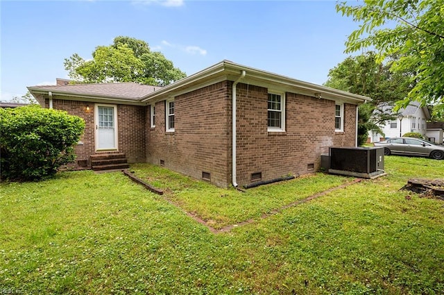 rear view of property featuring crawl space, entry steps, brick siding, and a yard