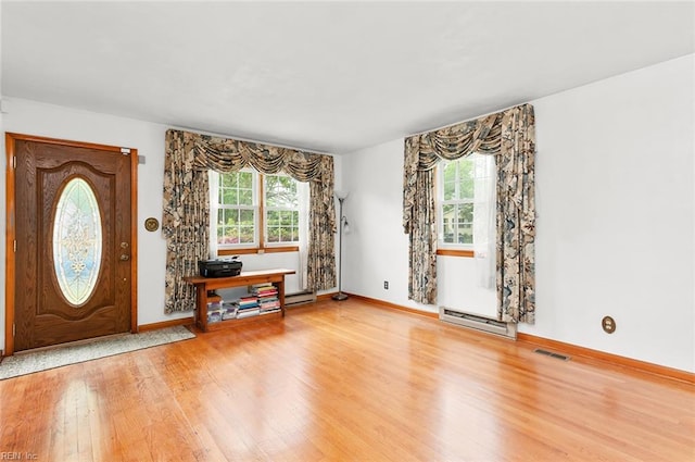 foyer featuring a baseboard heating unit, wood finished floors, and baseboards