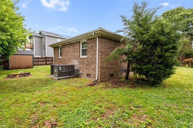 back of property featuring brick siding, central air condition unit, crawl space, a storage shed, and an outdoor structure