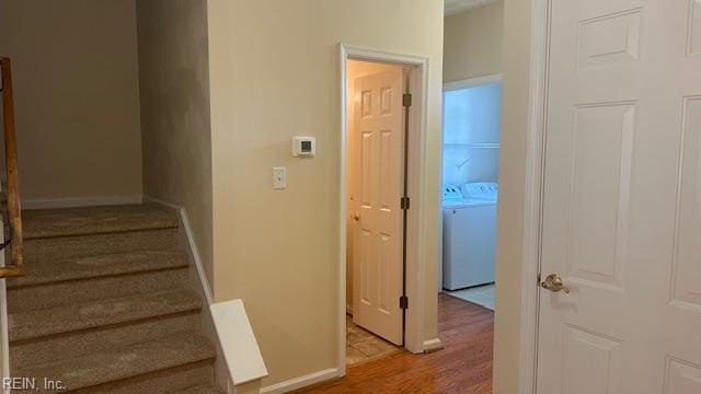 staircase with washing machine and dryer, wood finished floors, and baseboards