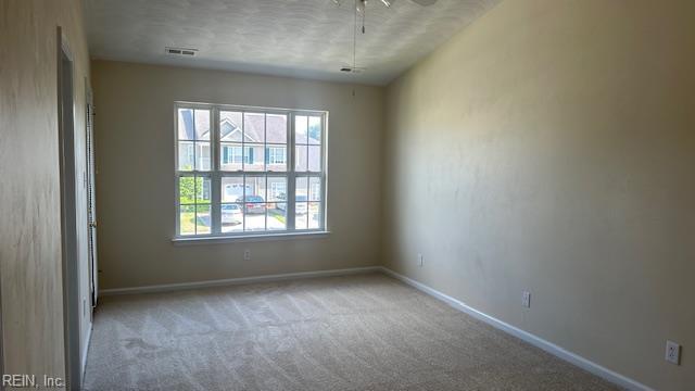 empty room with carpet, baseboards, a ceiling fan, and plenty of natural light